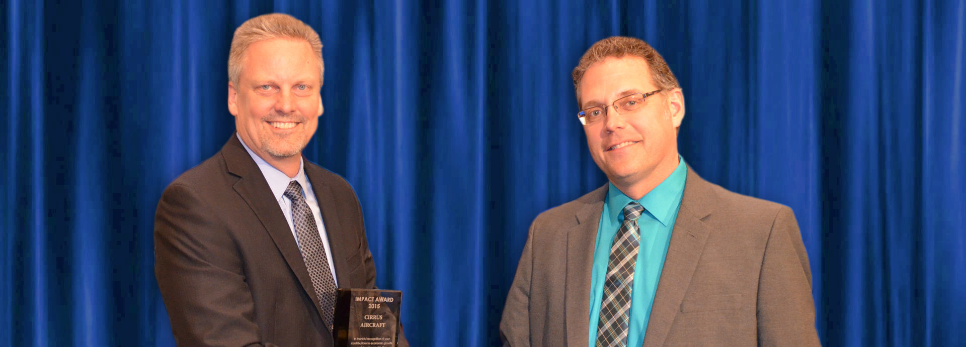 Two men shake hands at the Impact Award ceremony in Grand Forks