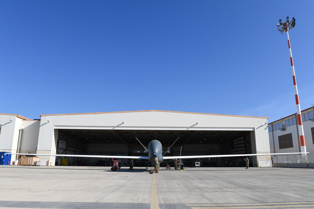 A global hawk drone sits outside of a hangar as it is cleaned.