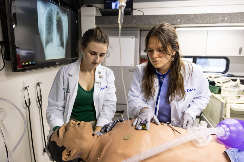 Two medical professionals assist to a dummy patient.
