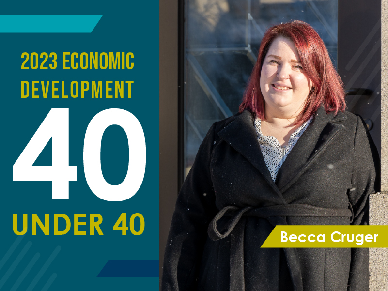 A graphic and picture of Becca Cruger smiling for a headshot with the sunshine brushing her face. The graphic includes words that read, 2023 Economic Development 40 under 40.