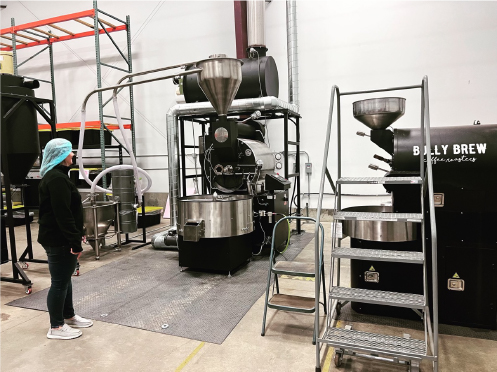 Sandi Luck stands looking at the coffee roaster at the ND Coffee Roastery in Grand Forks.