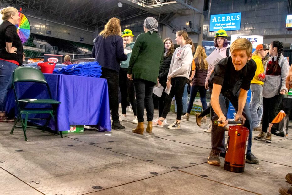 A student points a demonstration fire extinguisher at a demonstration fire at the 2022 Northern Valley Career Expo in Grand Forks North Dakota at the Alerus Center.