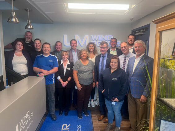 A group of leaders from the University of North Dakota, LM Wind Power, and the Grand Forks Region EDC stand together at the LM Wine Power offices in Grand Forks North Dakota during a tour.