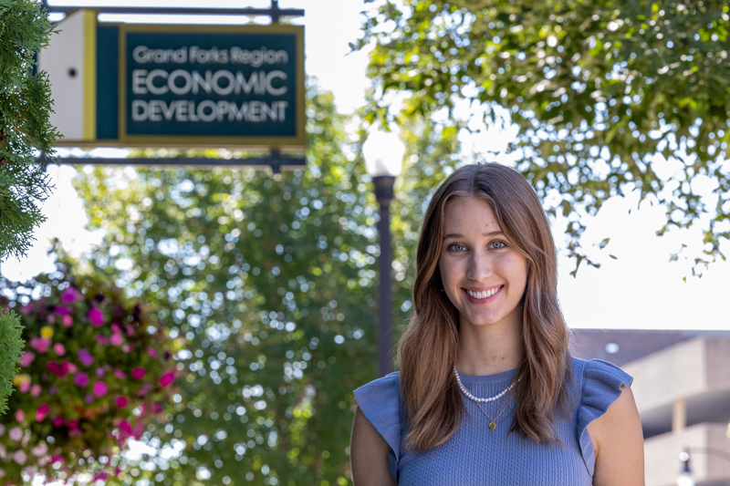 Meghan Ray stands in front of the Grand Forks Region EDC sign in downtown Grand Forks.