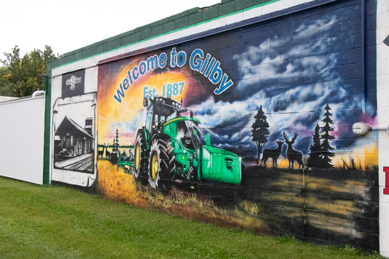 A mural on the side of a building reveals the words, "Welcome to Gilby!"