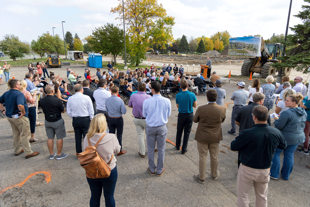 A group of community leaders sit and stand at the Career Impact Academy groundbreaking ceremony on Monday, October 2nd in Grand Forks, ND.