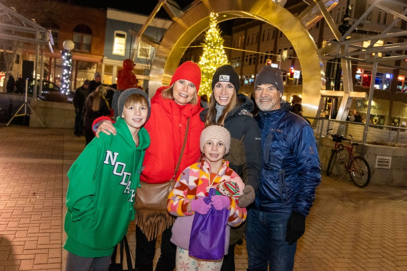 A family smiling at the camera at the Holydazzle Parade in Downtown Grand Forks.