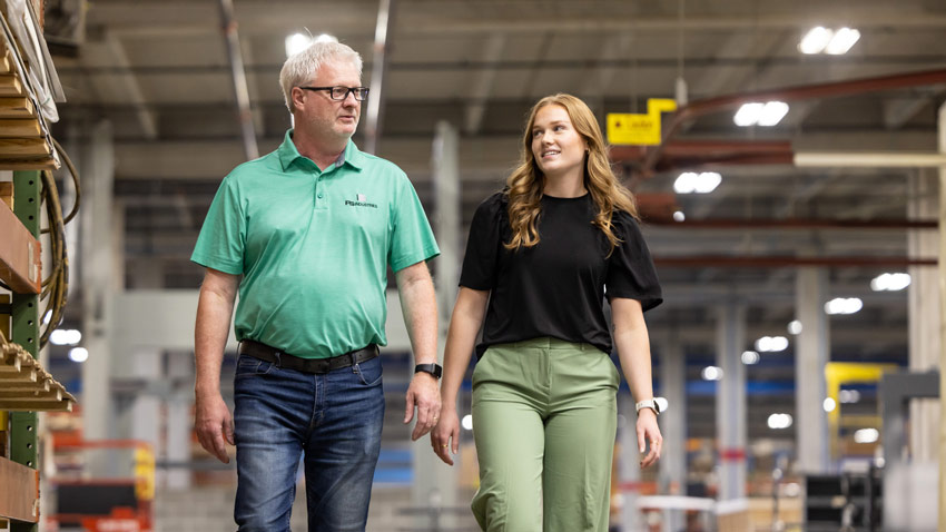Two people walk side by side in a warehouse in Grand Forks.