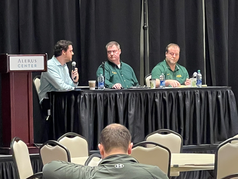Kevin Hatcher sits on a stage with two other panelists from NDSU at the 2024 International Crop Expo in Grand Forks.