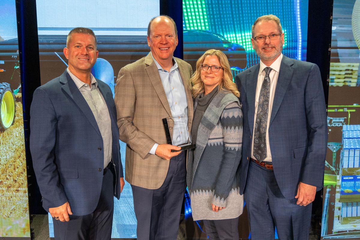 Karl Bollingberg stands with his wife, Twila, EDC board chair John Oncken, and President/CEO Keith Lund accepting the 2024 Klaus Thiessen Impact Award.