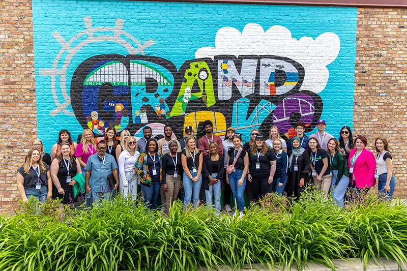 The InternGF Summer Cohort Series participants stands in front of the Grand Forks mural in town square of Downtown Grand Forks.