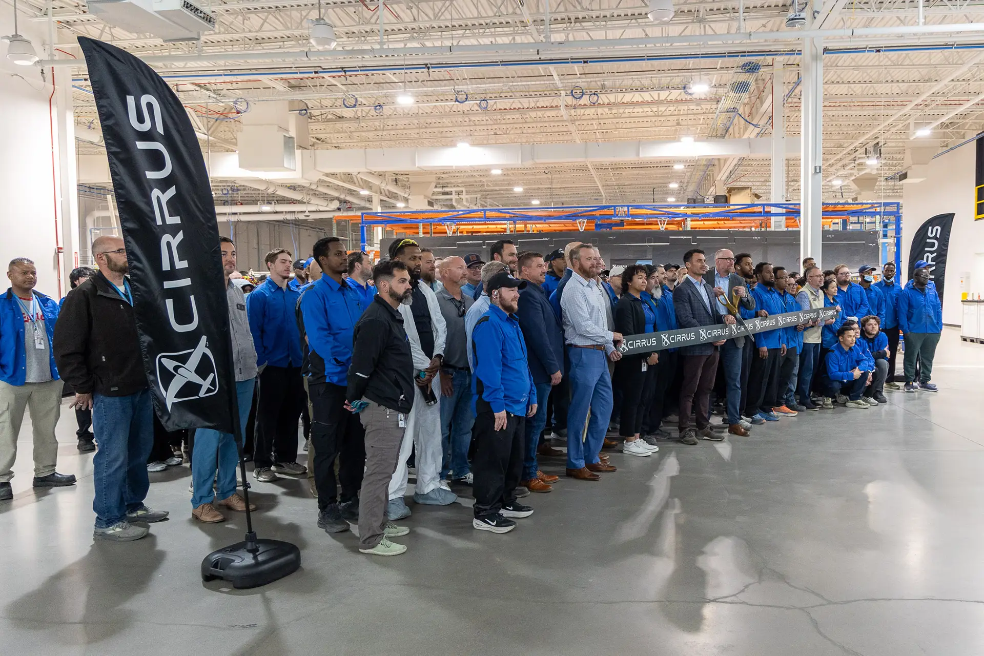 A group of Cirrus employees stand together cutting the ribbon on the new 30,000 sq ft expansion.