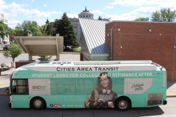 A bus with an image of a college girl sits outside a bus stop downtown