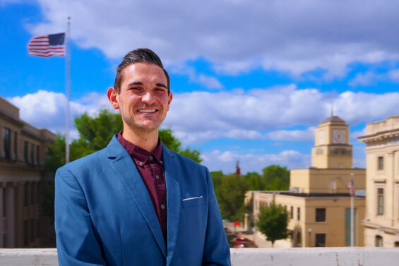 Mark Maliskey stands in front of a blue, cloudy sky with the Grand Forks Herald building in the background.