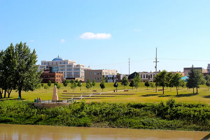 A point of view from the Red River of the North: the Grand Forks downtown, obelisk, and county building.