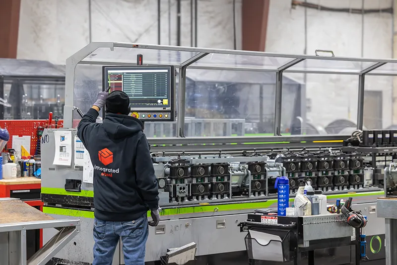 A manufacturing worker adjusts a screen on manufacturing equipment.