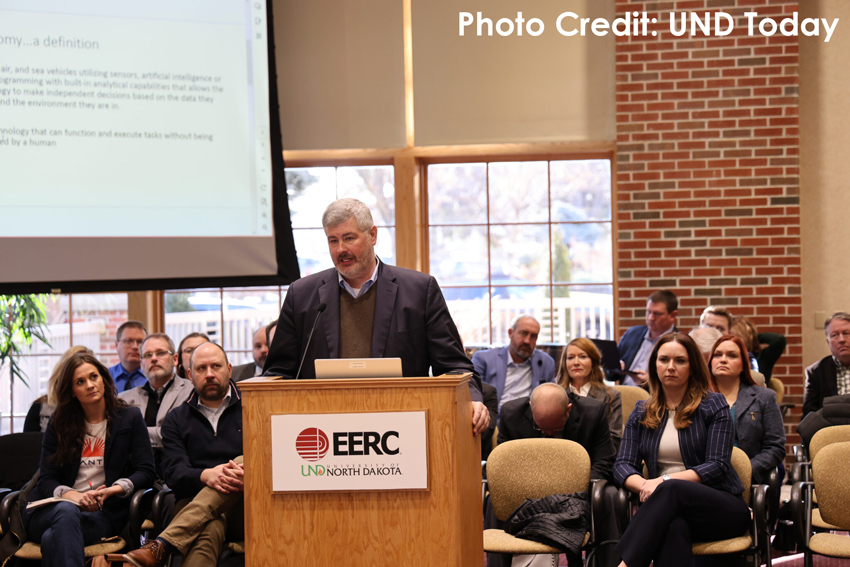 Tom Swoyer stands at a podium that reads EERC University of North Dakota speaking to the ND Interim Legislative Workforce Committee in December 2023.