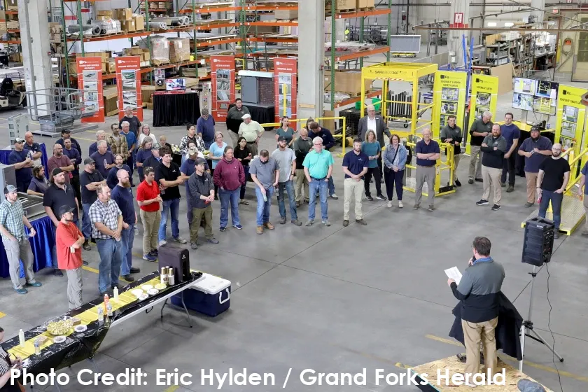 PS Industries employees stand together in their warehouse listening to a speaker at their 50th Anniversary Open House. Photo courtesy of Eric Hylden and the Grand Forks Herald.